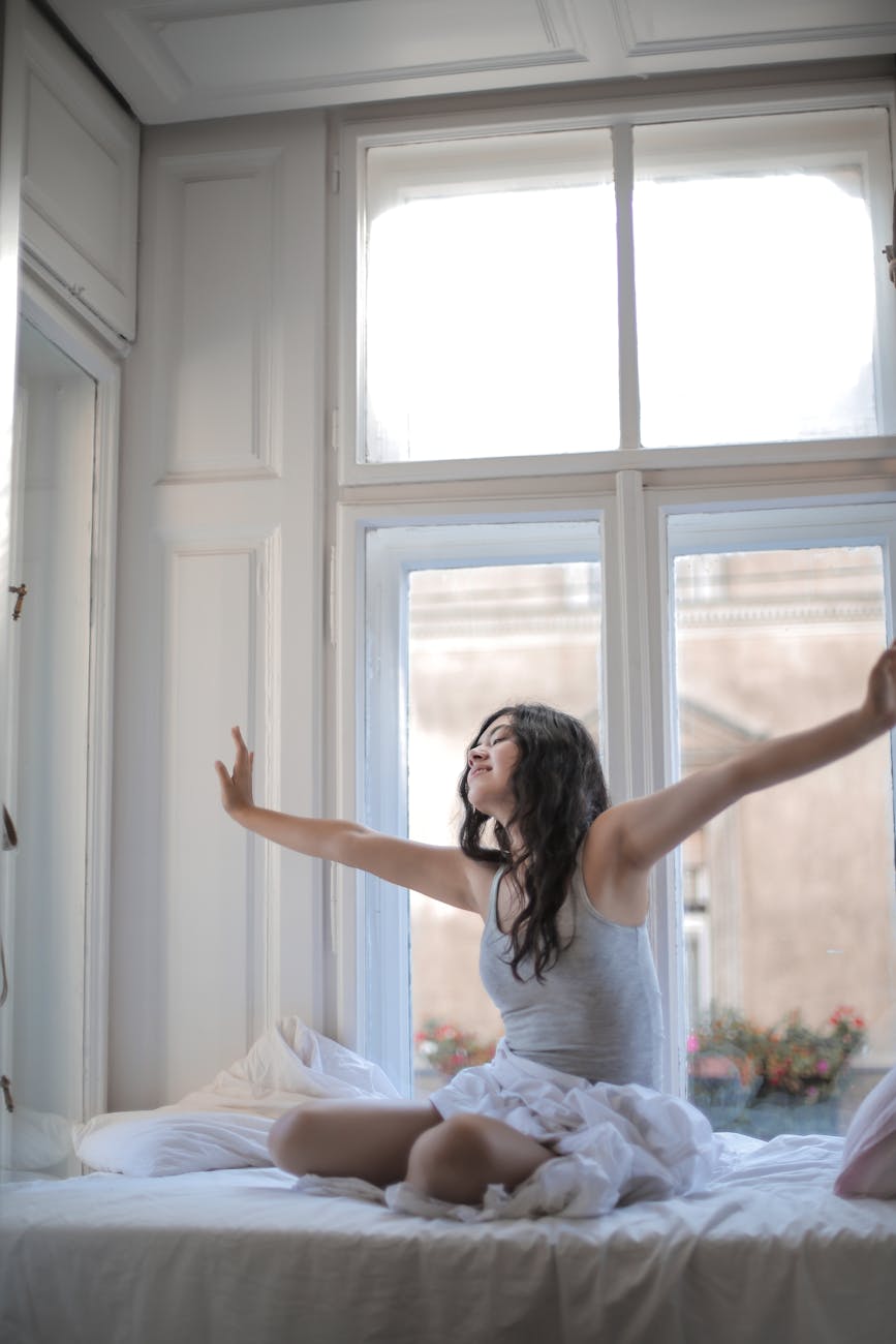 Person stretching calmly by a window with soft morning light.
